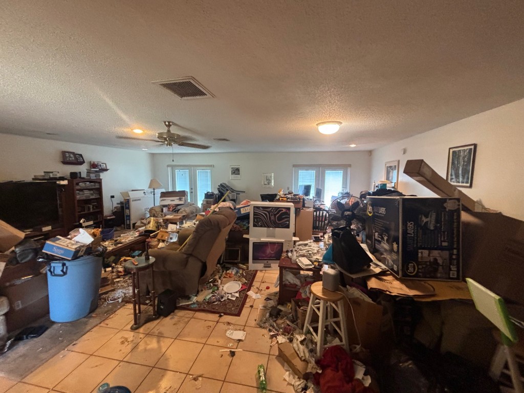 Cluttered home interior before a professional house cleanout in Orlando, Florida, featuring furniture, boxes, electronics, household debris, and accumulated junk.